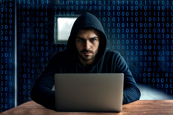 Fraudster in hoodie at laptop