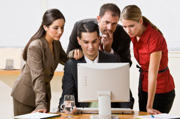 Manager and staff gathered around computer in professional office setting